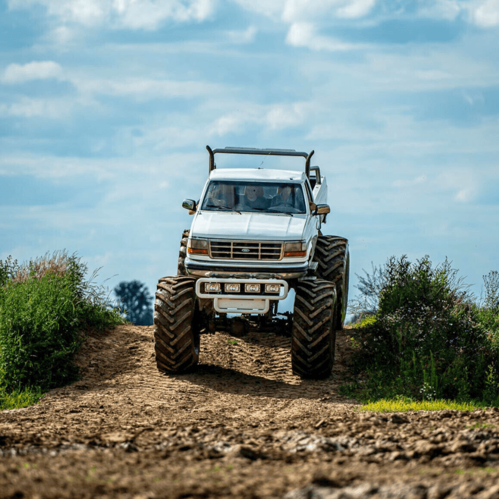 Ogromny monster truck, sunący po piaszczystej trasie w malowniczym otoczeniu, zachęca do przeżycia emocjonującej przygody w Gassy, niedaleko Warszawy.