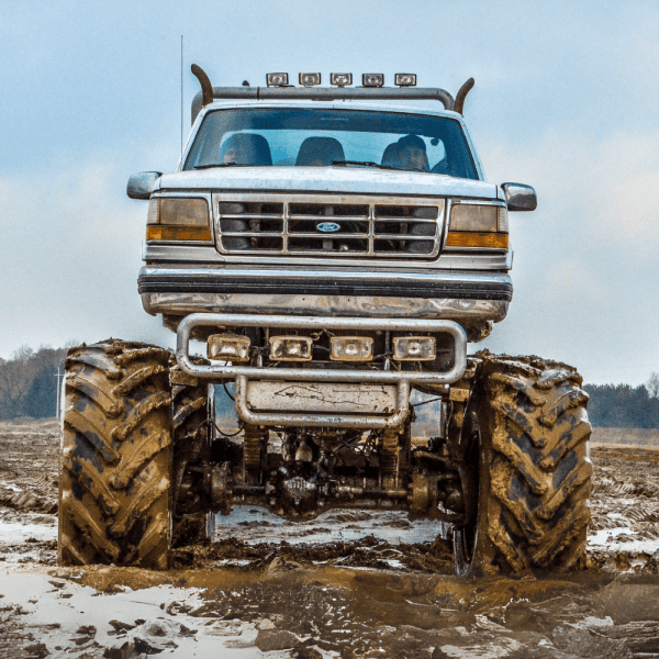 Potężny monster truck z ogromnymi oponami stoi gotowy do pokonywania błotnistych terenów.