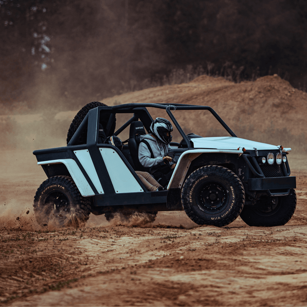Na grafice widać dynamiczną scenę z pojazdem terenowym w akcji, unoszącym kurz na piaszczystym torze, co idealnie oddaje emocjonującą atmosferę atrakcji z monster truckami pod Warszawą.