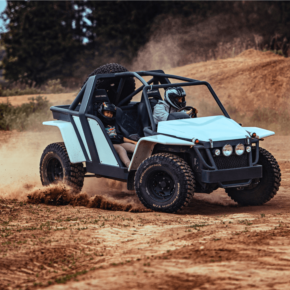 Wyrazista scena przedstawia off-roadowy pojazd w akcji, wzbudzający emocje zarówno dla dorosłych, jak i dzieci na terenowym torze w okolicach Gassy pod Warszawą.