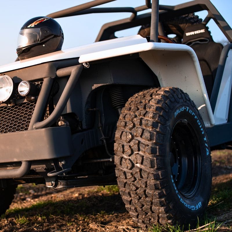 Zdjęcie przedstawia imponujący monster truck z solidnymi oponami i kaskiem na masce, przygotowany do emocjonujących przeżyć dla fanów mocnych wrażeń.