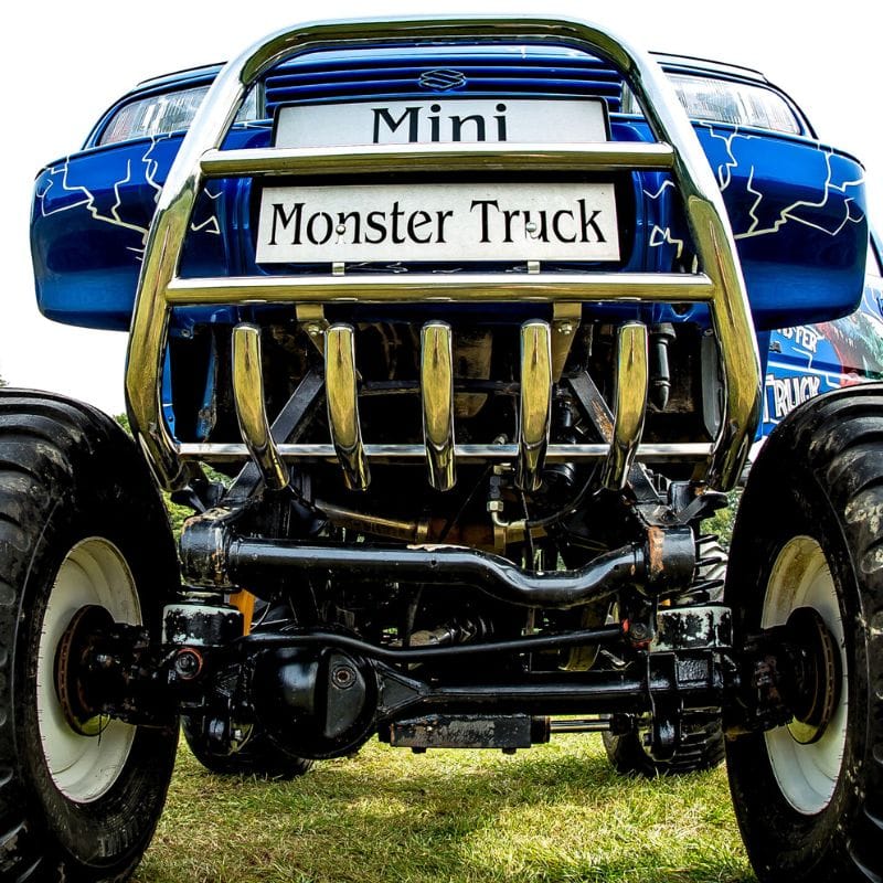 Na zdjęciu widać potężnego monster trucka z nisko położonej perspektywy, podkreślającej jego masywne opony i charakterystyczne chromowane detale.