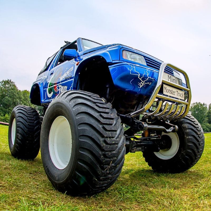 Na zdjęciu widzimy niebieskiego mini monster trucka o masywnych oponach, zapraszającego na emocjonujące atrakcje w Gassy pod Warszawą, gdzie zabawa czeka zarówno dorosłych, jak i dzieci.